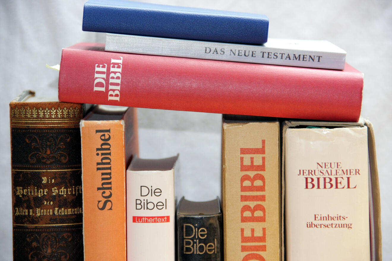 Verschiedene Ausgaben der Bibel und verwandte Texte auf einem Tisch angeordnet.